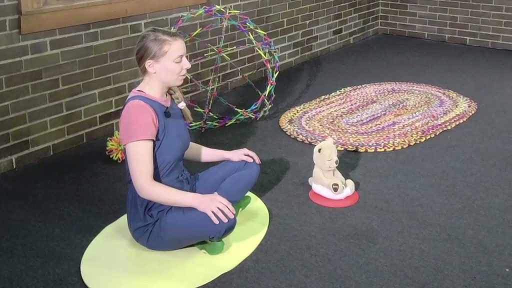 A woman sitting on a mat with a dog on it