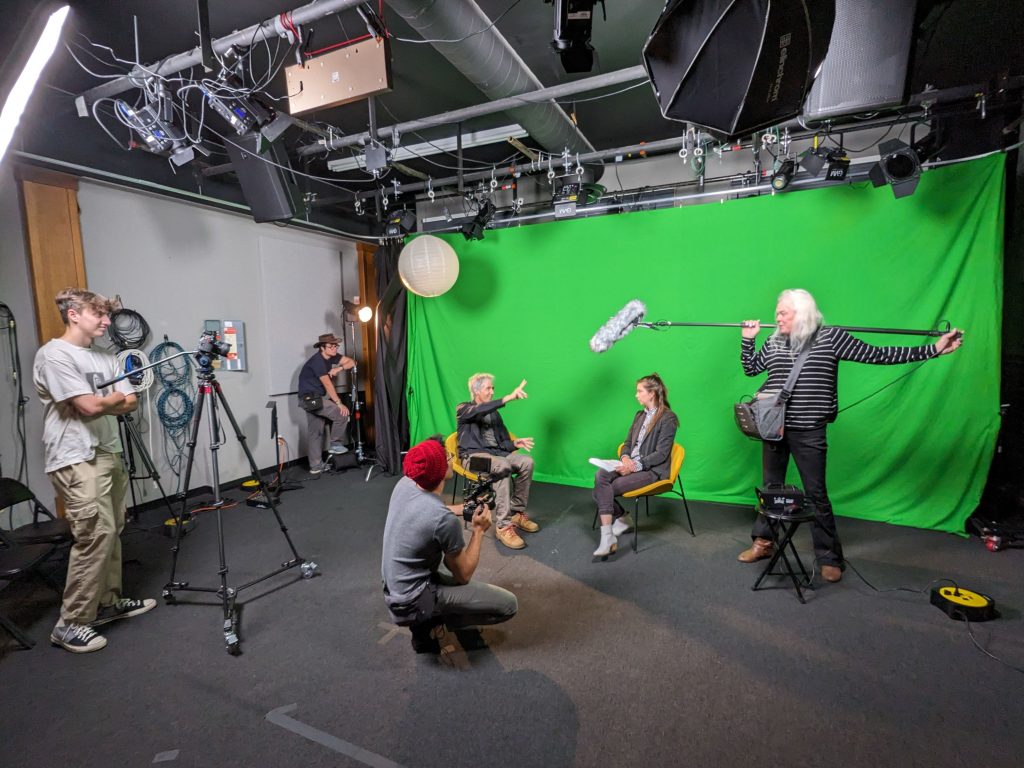 A group of individuals gathered around a green screen for a photoshoot
