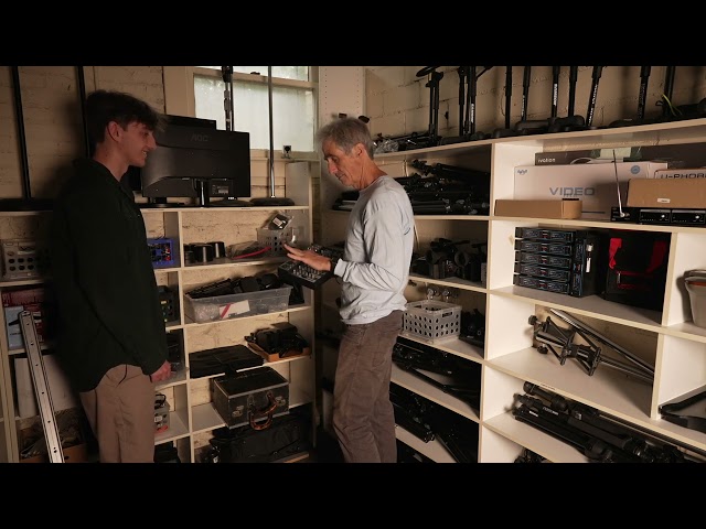 two men standing in a room full of electronics and technology gadgets