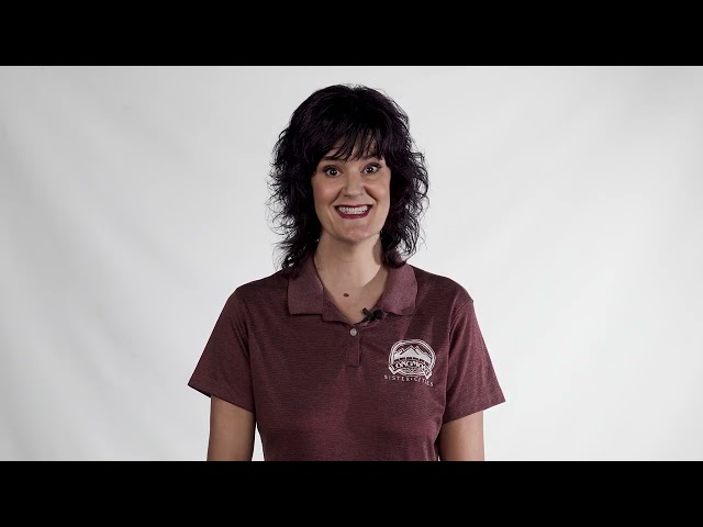 A woman in a maroon shirt is smiling brightly
