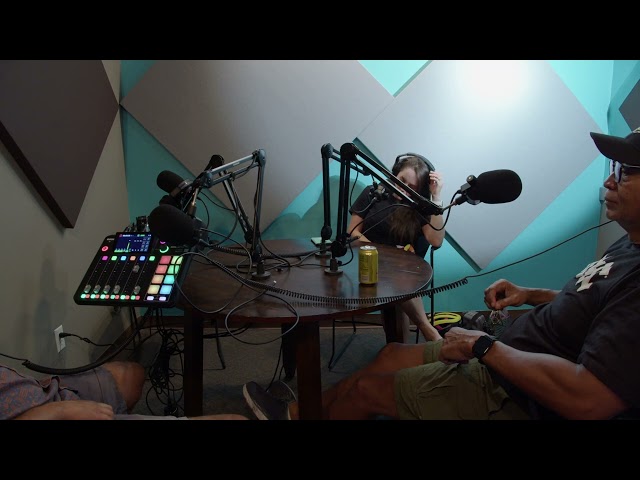 A group of podcasters sitting around a table with microphones